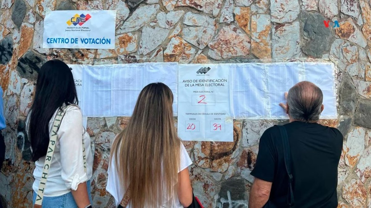 Votantes revisan las listas de electores en la pared de un centro de votación del CNE durante las elecciones presidenciales de Venezuela de 2024