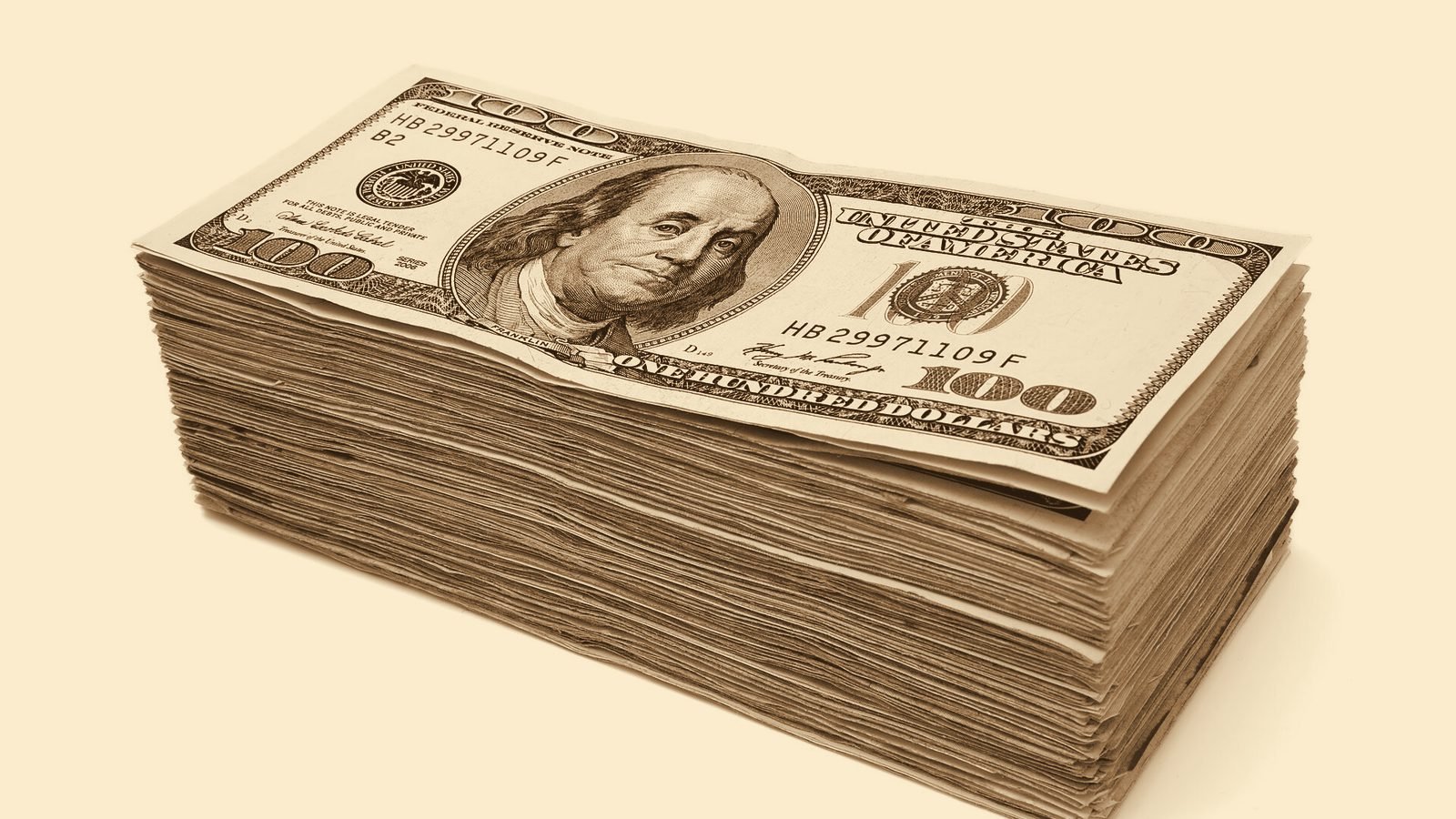 Fajo de billetes de cien dólares estadounidenses sobre fondo claro, en tono sepia